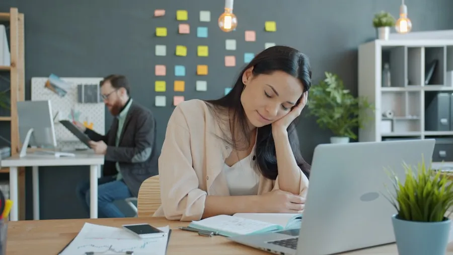 Woman resting her head on her hand at a desk, looking tired in the afternoon